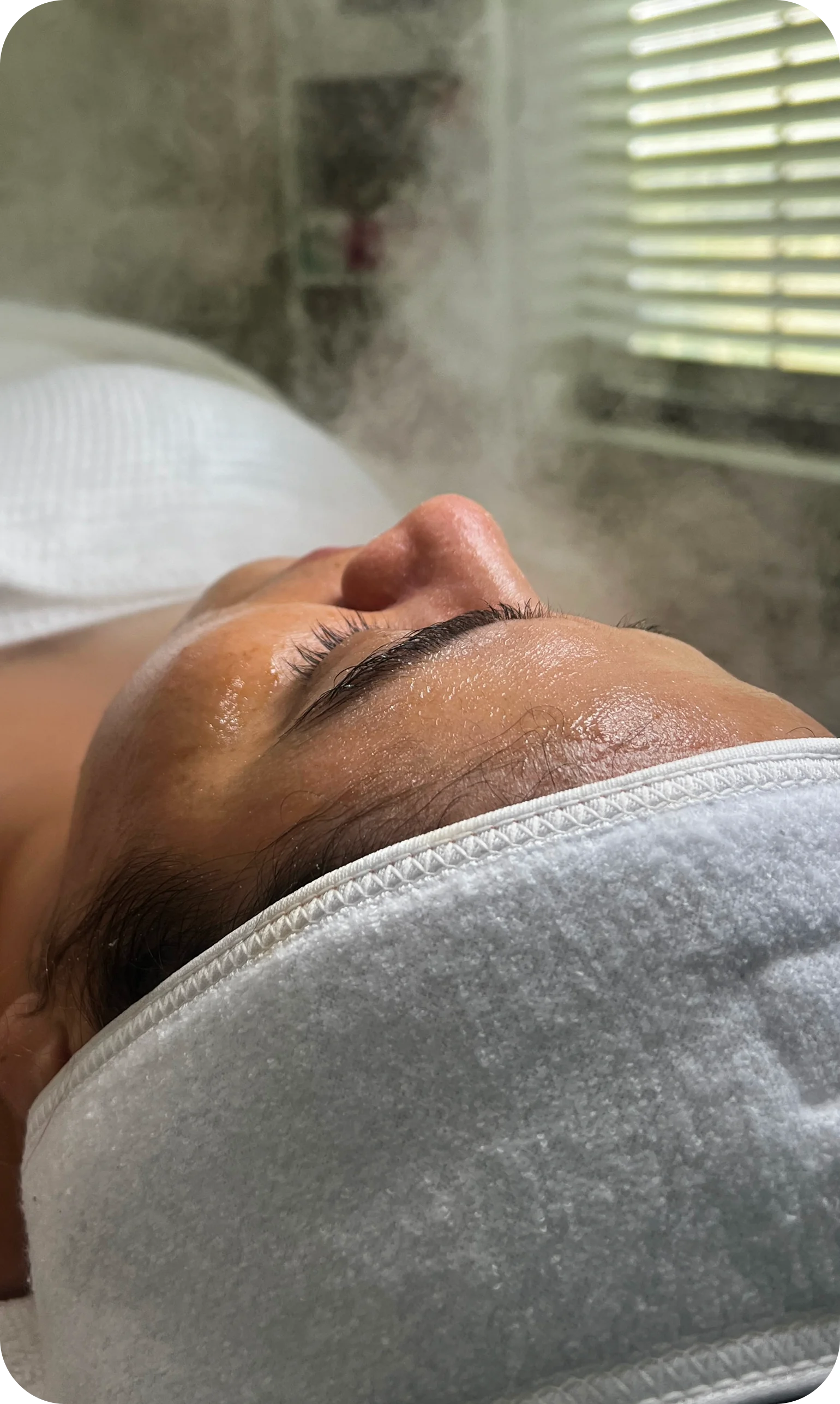 Clienta recostada recibiendo vapor facial en la cabina.